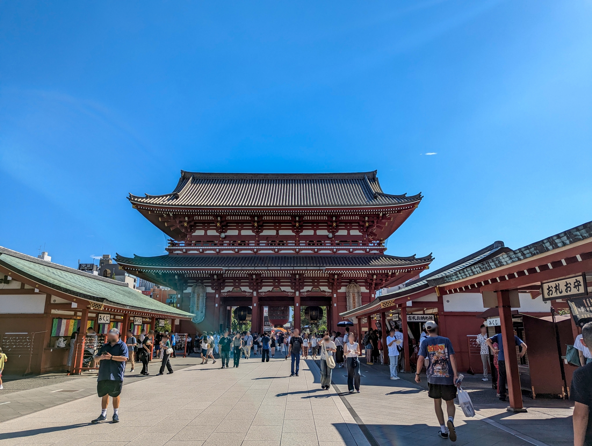 浅草寺の本堂に向かって参道を歩く人々。青空の下に広がる歴史ある風景。